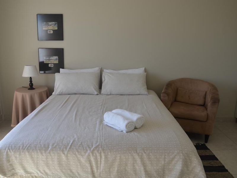A neutrally decorated bedroom featuring tiled flooring and a simple layout, offering a comfortable and functional living space.