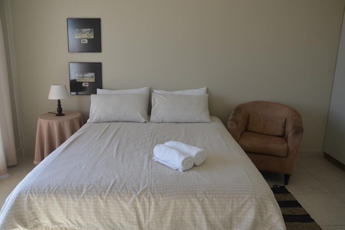 A neutrally decorated bedroom featuring tiled flooring and a simple layout, offering a comfortable and functional living space.
