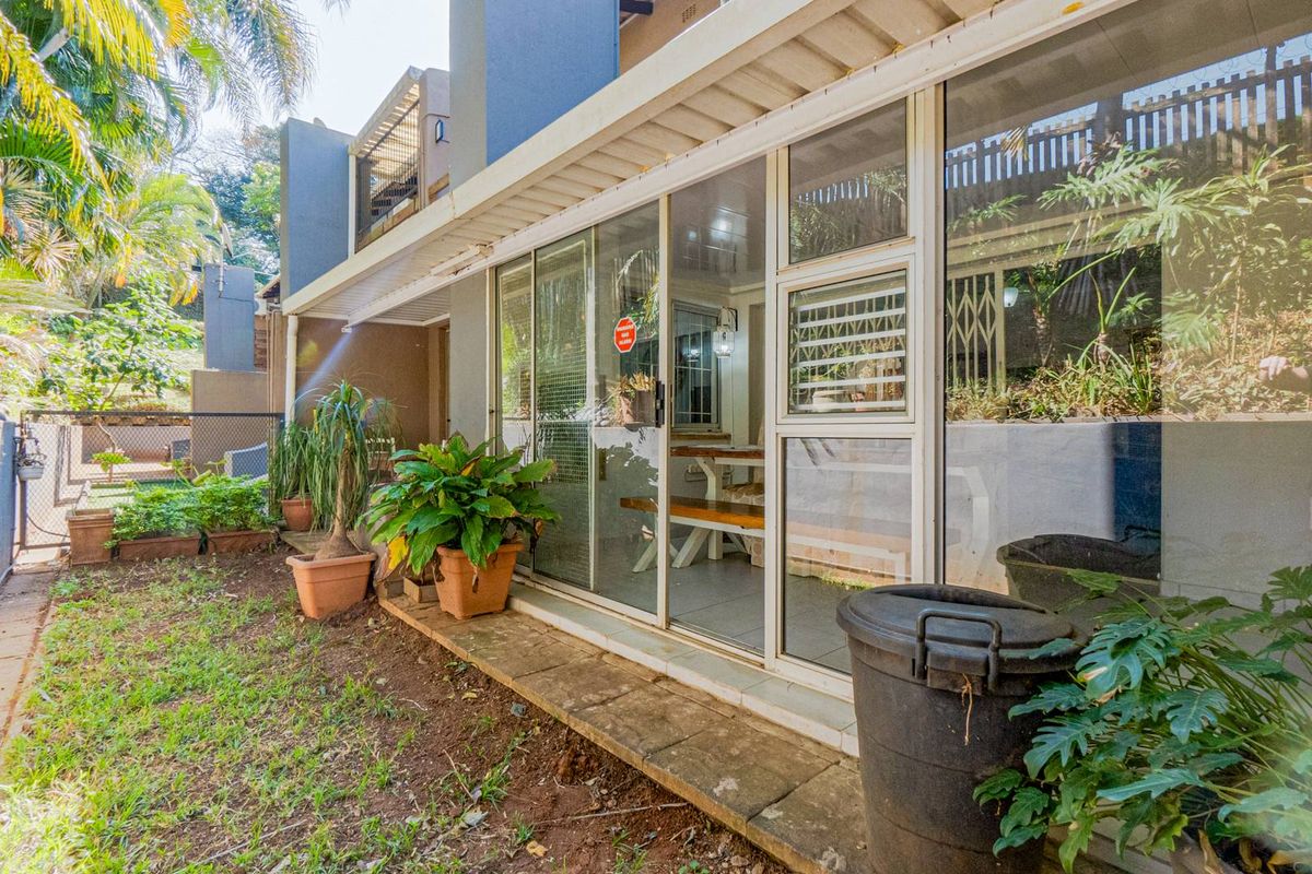 Rear exterior view of the townhouse featuring a paved patio area, sliding glass doors, and access to the garden space.