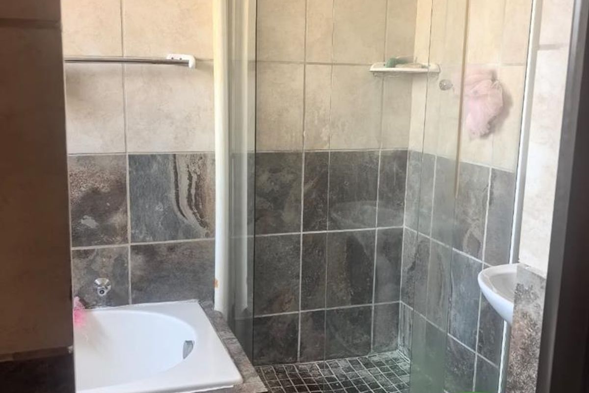 A functional bathroom featuring a built-in bathtub, a separate glass-enclosed shower, and tiled wall finishes.
