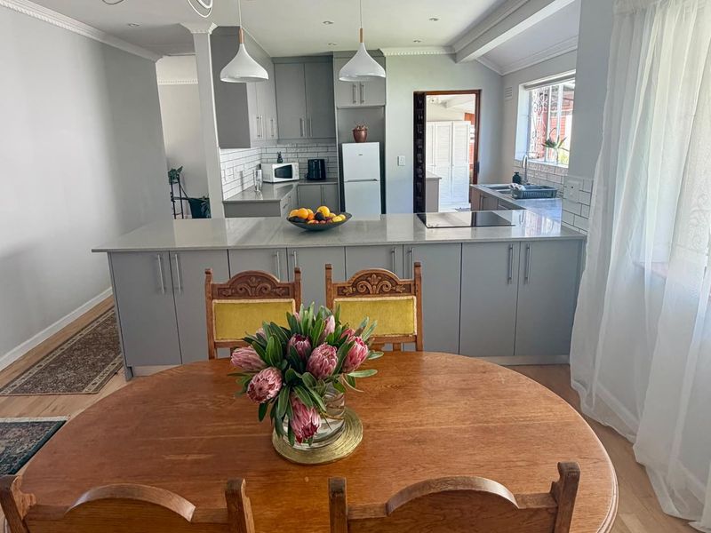 Modern open-plan kitchen featuring a central island with quartz countertops, subway tile backsplash, and contemporary grey cabinetry, seamlessly flowing into the dining area.