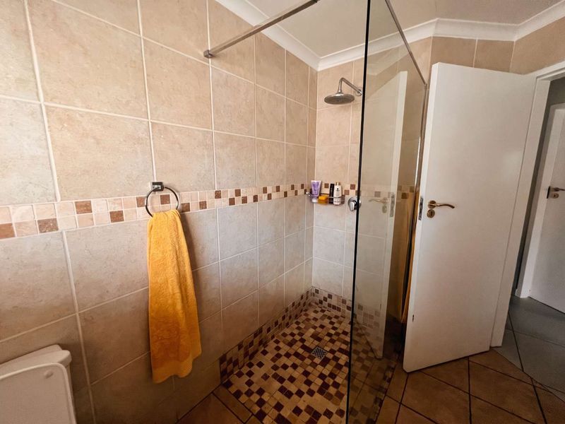 A functional bathroom featuring a walk-in shower with a glass screen, tiled walls, and tiled flooring.