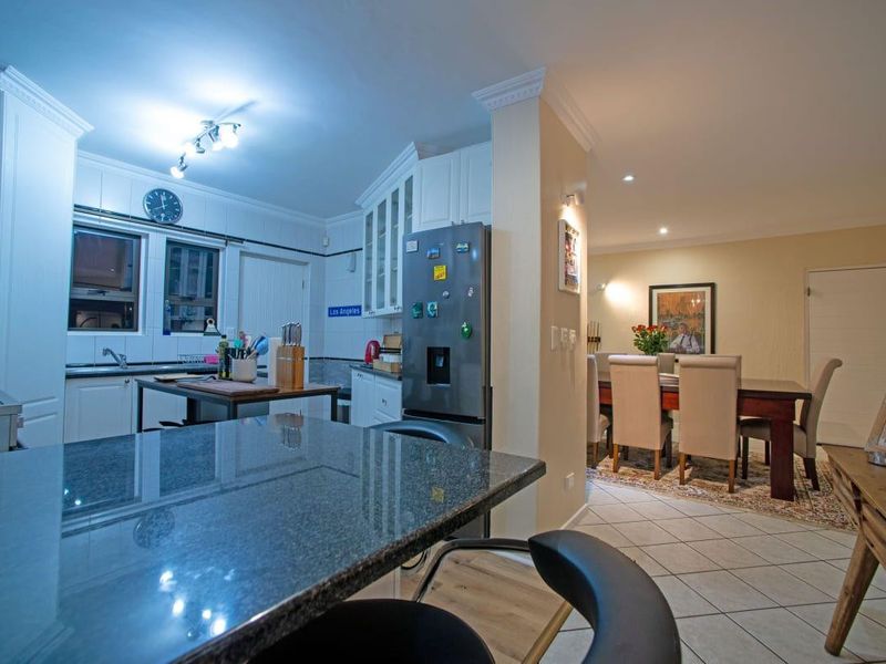 Open-plan kitchen and dining area featuring granite countertops, white cabinetry, and tiled flooring, creating a functional and connected living space.
