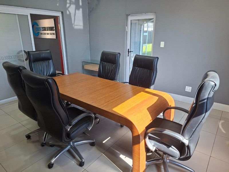 A functional office space featuring tiled flooring, a glass sliding door, and a secondary exterior door, with visible ceiling water staining.