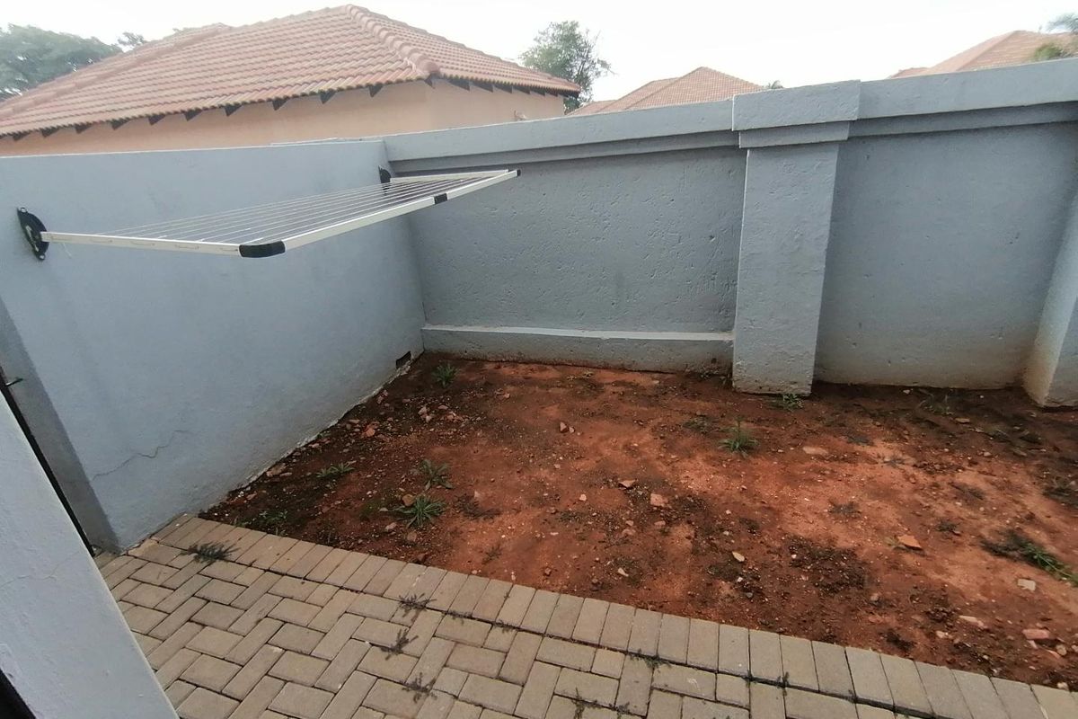 A small rear courtyard area featuring a paved section, boundary walls, and an unlandscaped soil patch, providing a blank canvas for outdoor improvement.