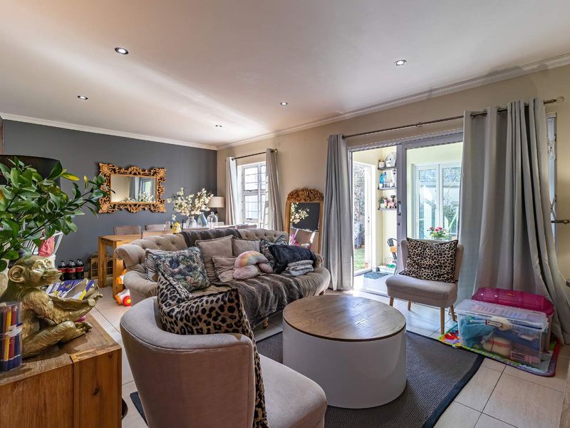 Spacious open-plan living and dining area featuring tiled flooring, recessed downlighting, and large sliding glass doors providing direct access to the patio.