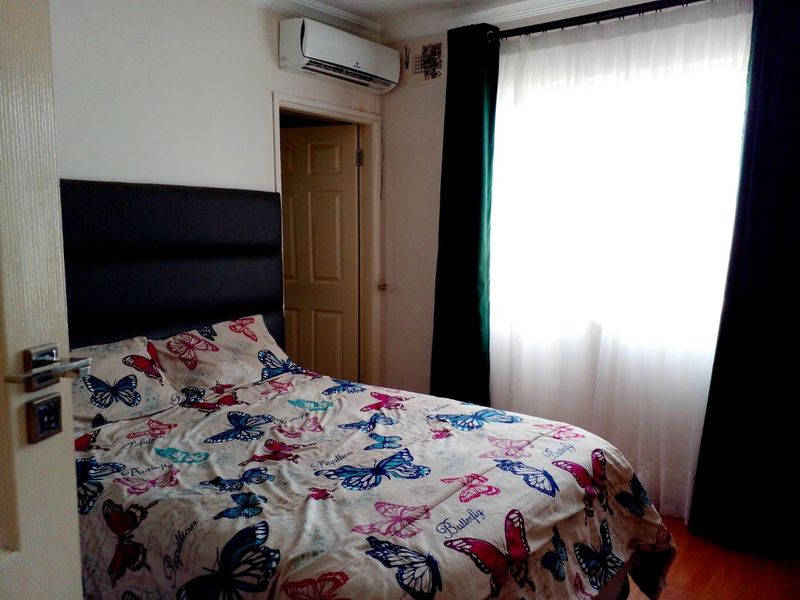 A functional bedroom featuring laminate flooring, coving, and a wall-mounted split-system air conditioning unit.