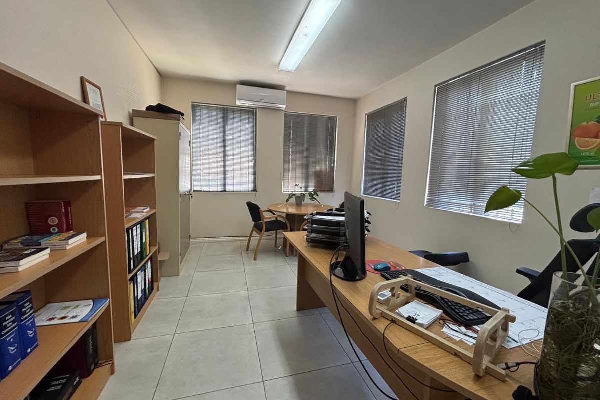 A functional office space featuring tiled flooring, air conditioning, and multiple windows with venetian blinds, providing a bright and practical work environment.