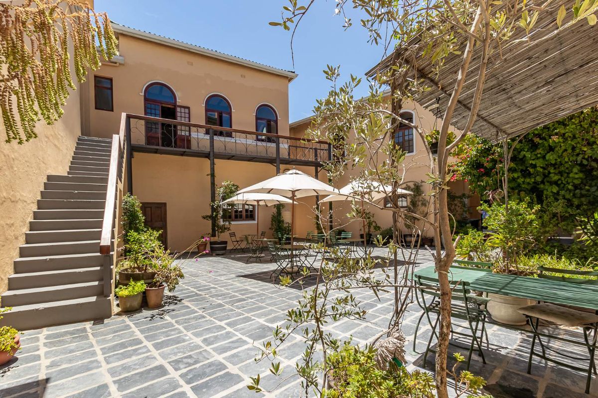 A spacious Mediterranean-style courtyard featuring stone paving, an external staircase, and a covered patio area, ideal for outdoor dining and relaxation.