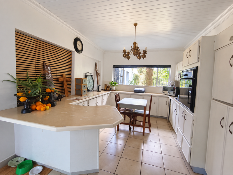 Spacious kitchen featuring ample built-in cabinetry, a breakfast bar, built-in oven, and tiled flooring, offering a functional layout with potential for modern updates.
