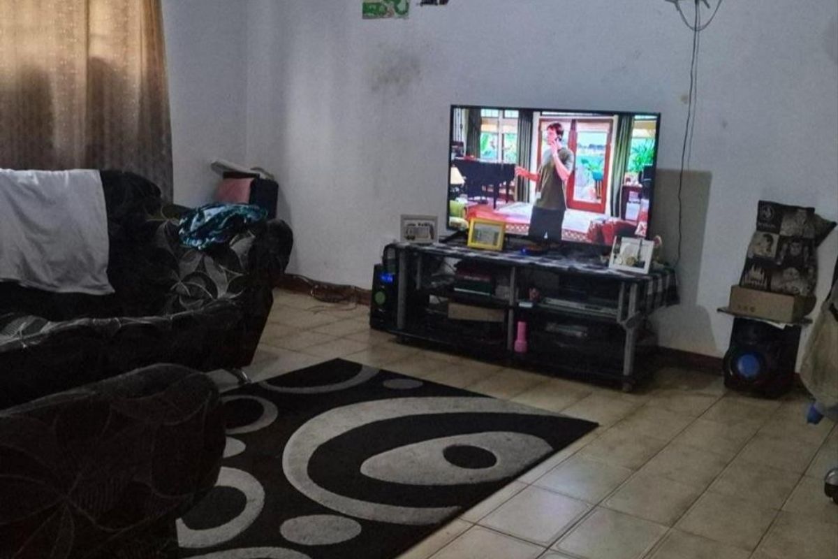 A living room area featuring tiled flooring and neutral wall finishes, currently used as a casual lounge space.