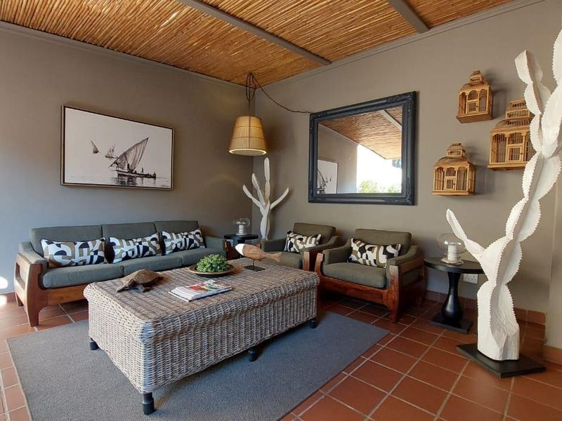 A covered patio area featuring a rustic thatched ceiling and terracotta floor tiles, providing a comfortable outdoor living space.