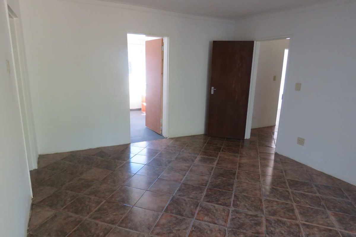 An empty room featuring tiled flooring and multiple doorways leading to adjacent spaces, providing a neutral foundation for interior design.