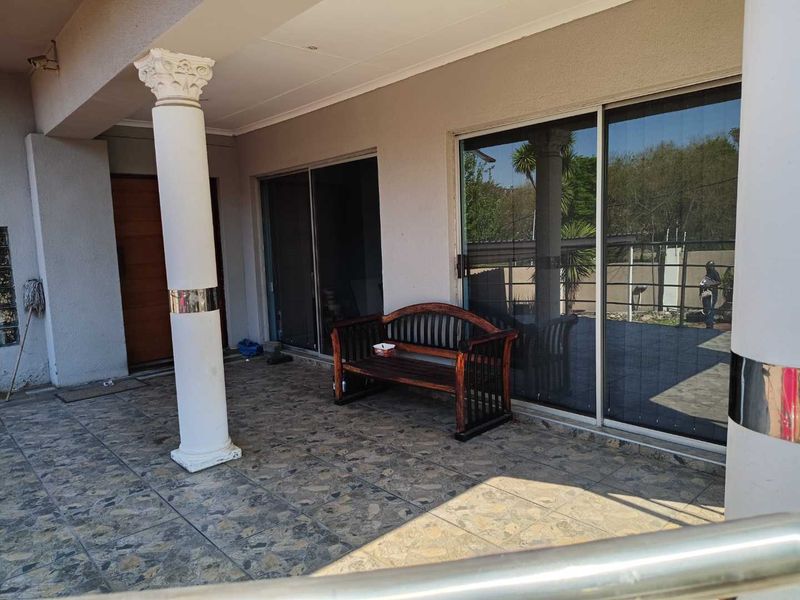 A covered patio area featuring tiled flooring, decorative columns, and large sliding glass doors providing access to the interior living space.