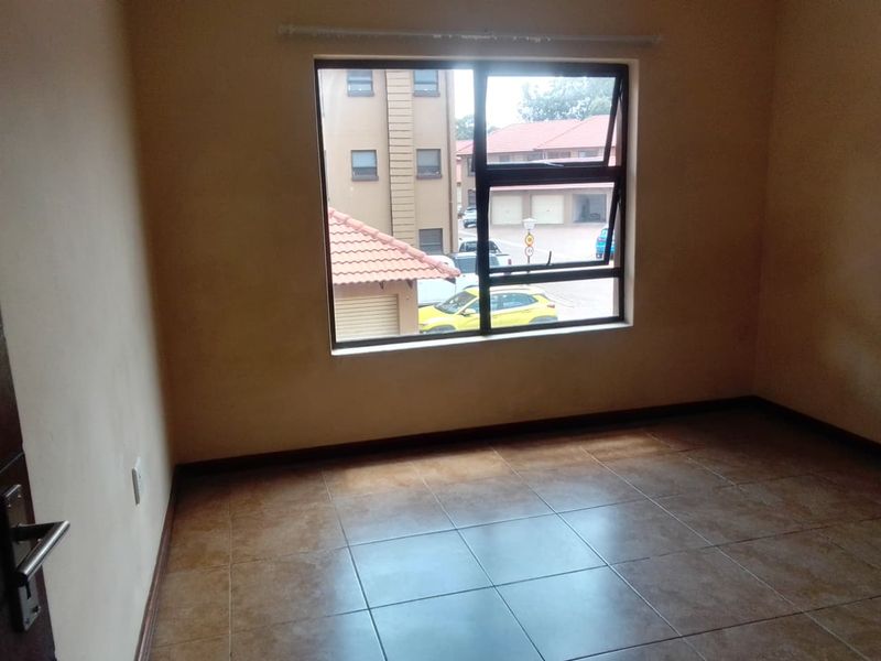 An empty bedroom featuring tiled flooring and an aluminium window frame, offering a neutral space ready for personalization.