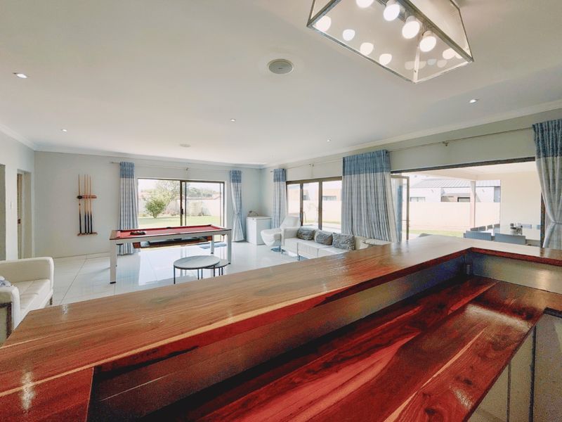 Spacious open-plan living area featuring a built-in wooden bar, tiled flooring, and large sliding doors providing seamless access to the outdoor patio.
