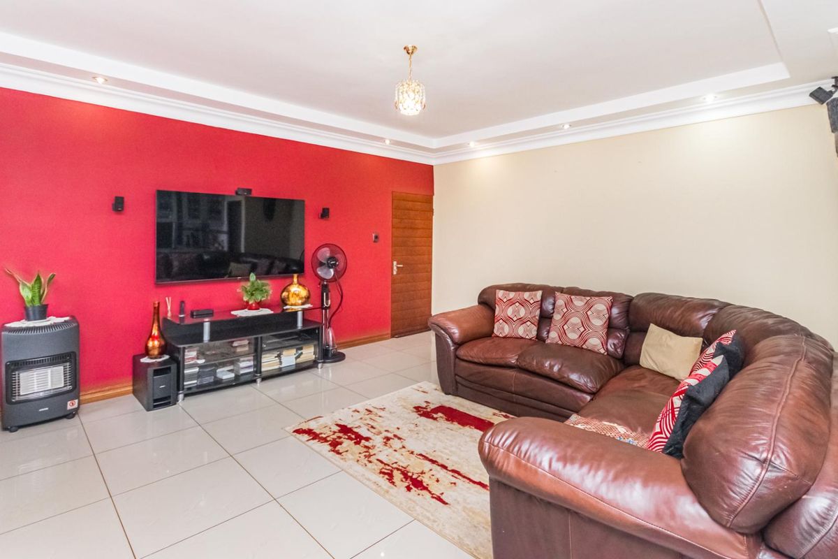 Spacious living room featuring tiled flooring, recessed ceiling lighting, and a bold red accent wall.