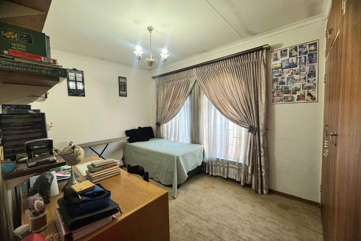 A functional bedroom featuring built-in wooden cabinetry, carpeted flooring, and a central light fixture, offering a comfortable and practical living space.