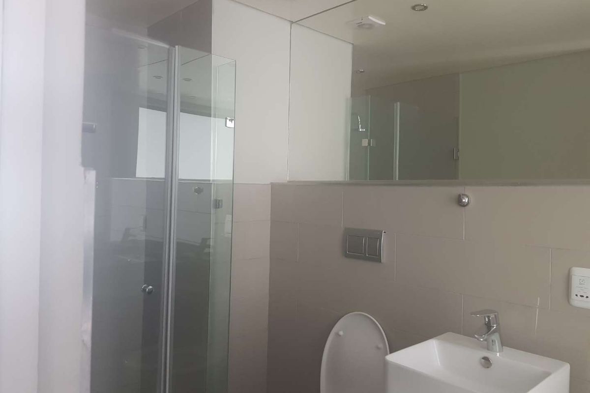 A modern bathroom featuring a glass shower enclosure, a vessel sink with chrome faucet, and a large wall mirror.