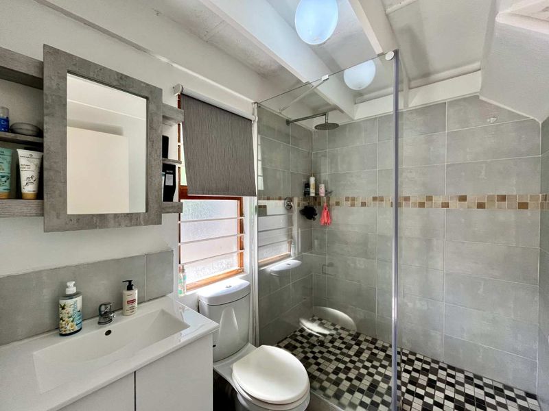 Modern bathroom featuring a walk-in shower with a rain shower head, mosaic floor tiling, a vanity cabinet, and a wall-mounted mirror cabinet.
