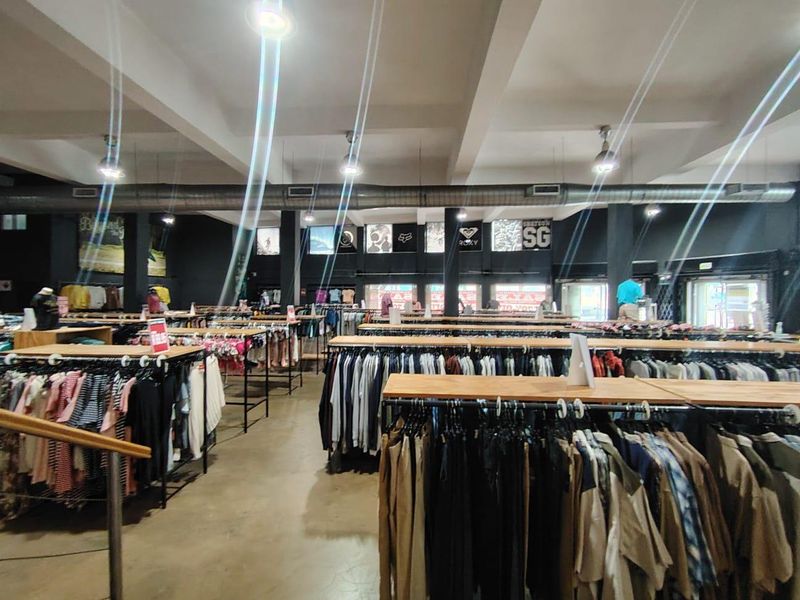 Spacious open-plan retail floor featuring industrial-style exposed ductwork, recessed lighting, and polished concrete flooring, currently configured for apparel display.