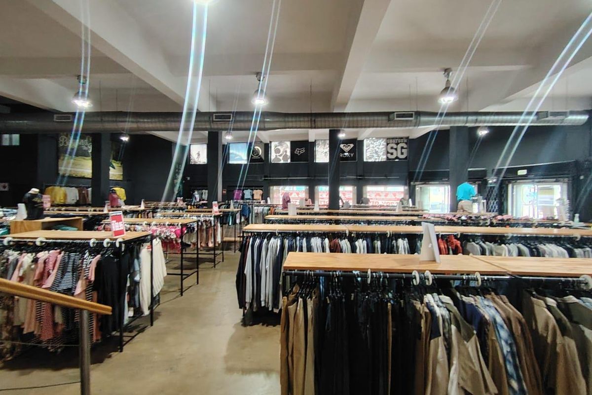 Spacious open-plan retail floor featuring industrial-style exposed ductwork, recessed lighting, and polished concrete flooring, currently configured for apparel display.