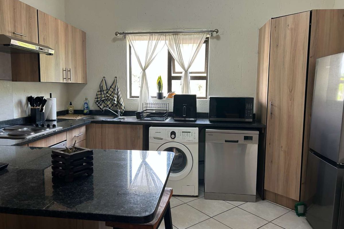 Functional kitchen featuring wood-look cabinetry, granite countertops, integrated appliances, and tiled flooring, offering a practical and well-organized cooking space.