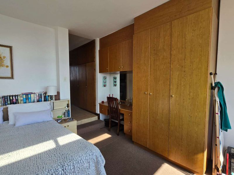 Bedroom featuring extensive built-in wooden cabinetry, a integrated vanity area, and carpeted flooring.