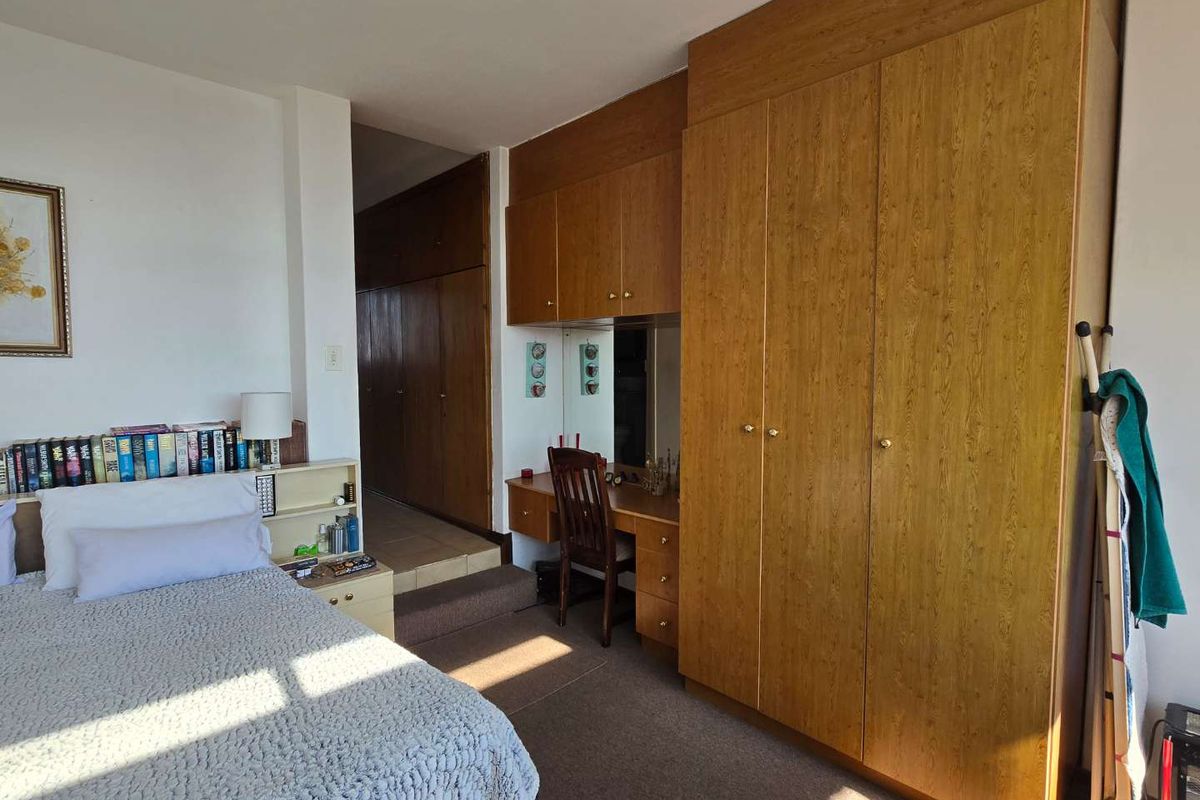 Bedroom featuring extensive built-in wooden cabinetry, a integrated vanity area, and carpeted flooring.