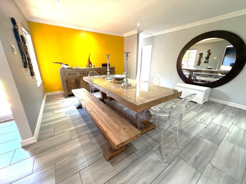 A bright dining room featuring wood-look tile flooring, recessed lighting, and decorative crown molding, creating a modern and inviting space for meals.