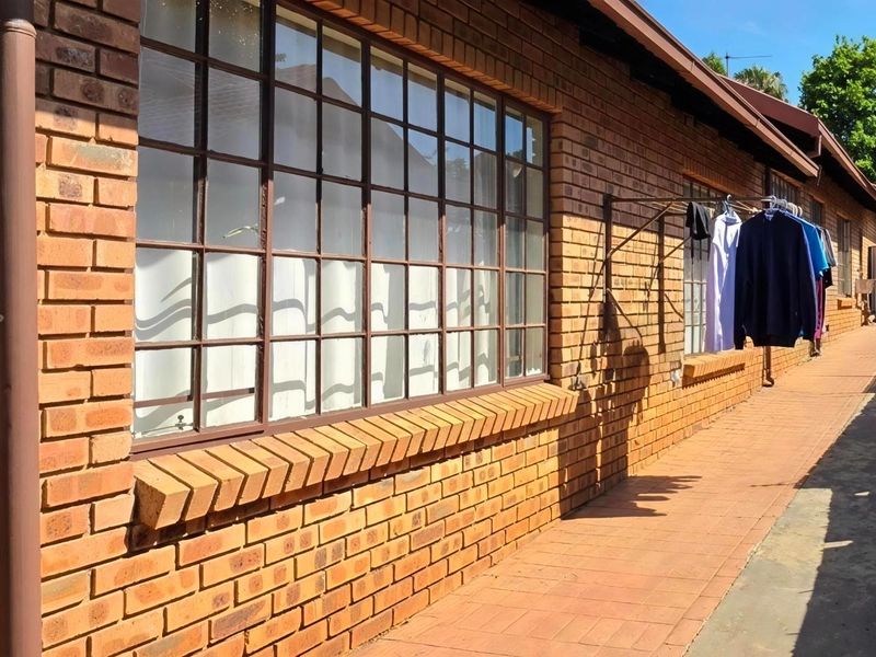 A side view of the townhouse exterior featuring face brick walls, steel-framed windows, and a paved walkway.