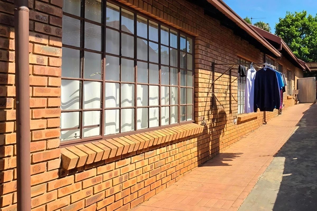 A side view of the townhouse exterior featuring face brick walls, steel-framed windows, and a paved walkway.