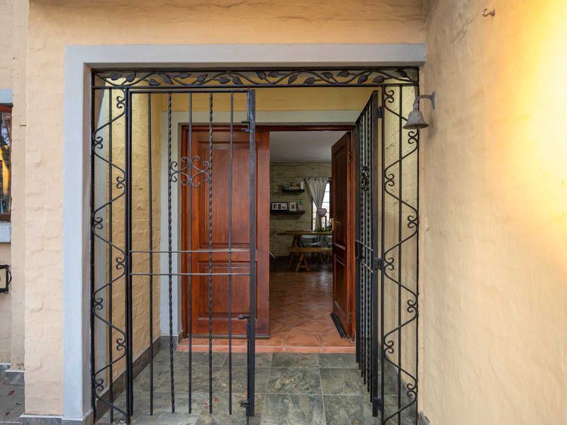 Entrance area featuring a decorative wrought iron security gate, double wooden doors, and tiled flooring, providing a secure and welcoming access point to the home.