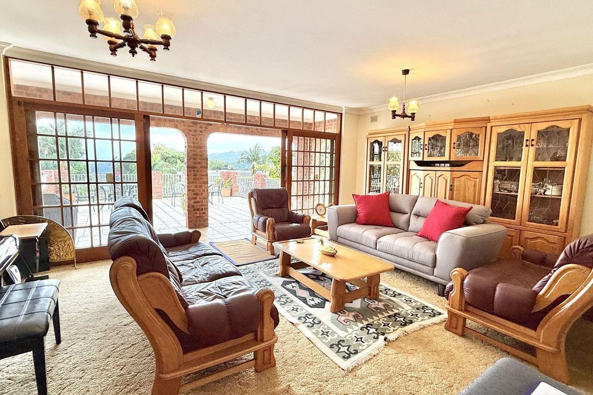 Spacious living room featuring large wooden-framed sliding doors opening onto a covered patio, with built-in display cabinetry and traditional lighting fixtures.