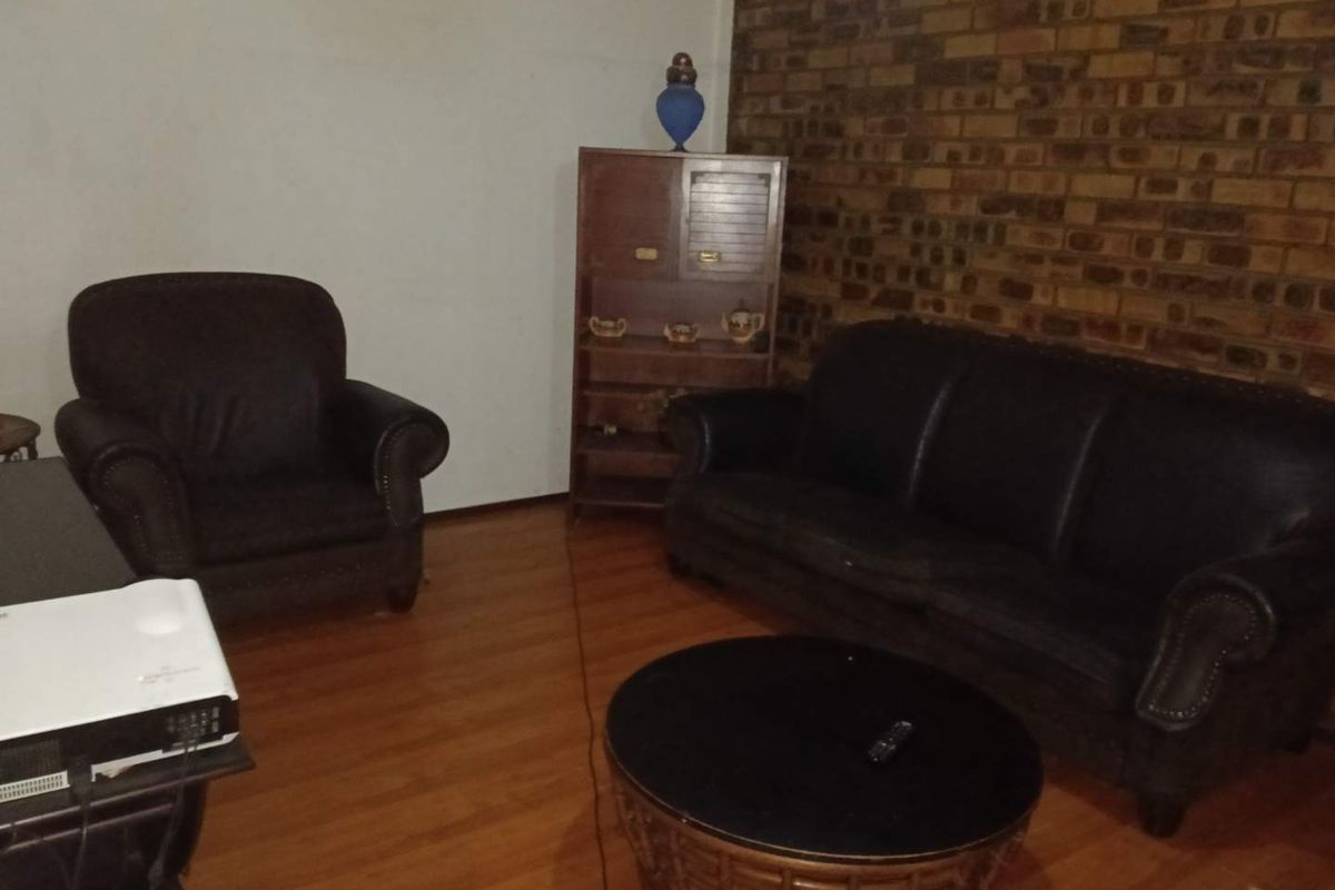 A living room featuring laminate flooring and an exposed brick feature wall, providing a rustic aesthetic base for interior design updates.