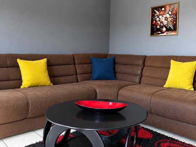 A well-maintained living room area featuring neutral grey walls, tiled flooring, and coved ceiling detailing.