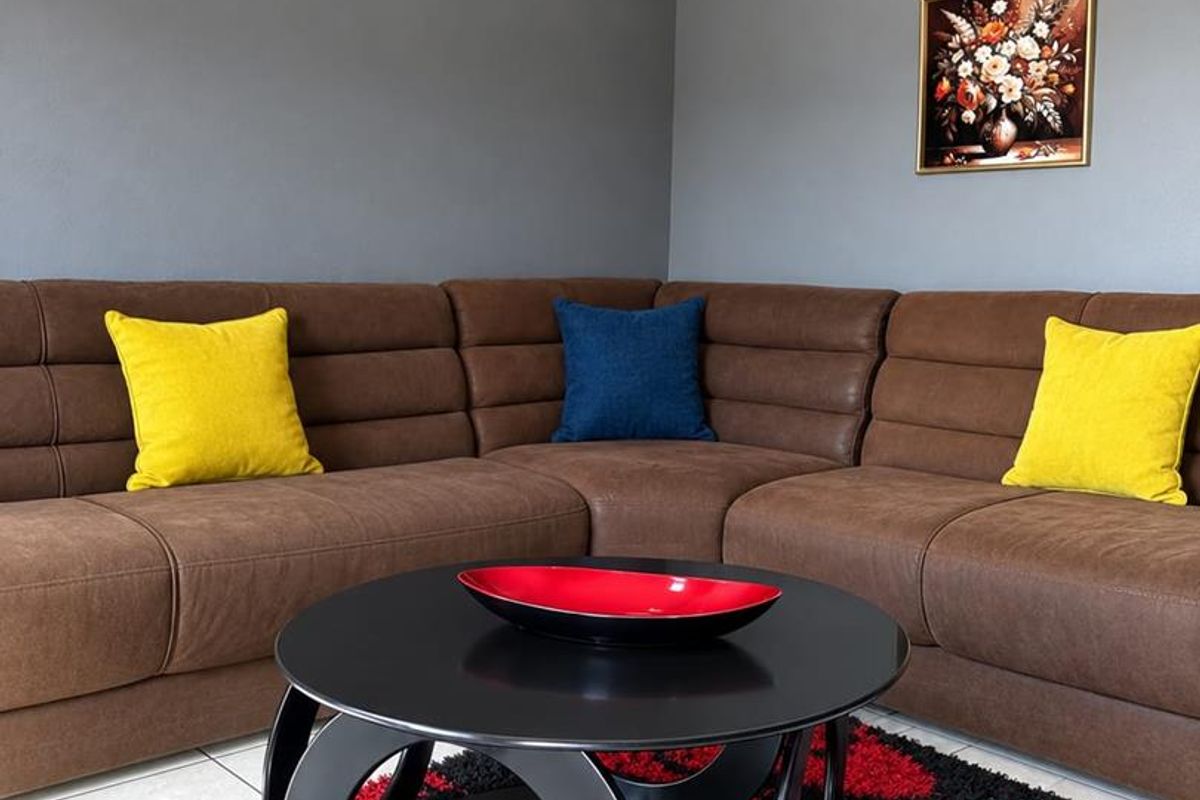 A well-maintained living room area featuring neutral grey walls, tiled flooring, and coved ceiling detailing.