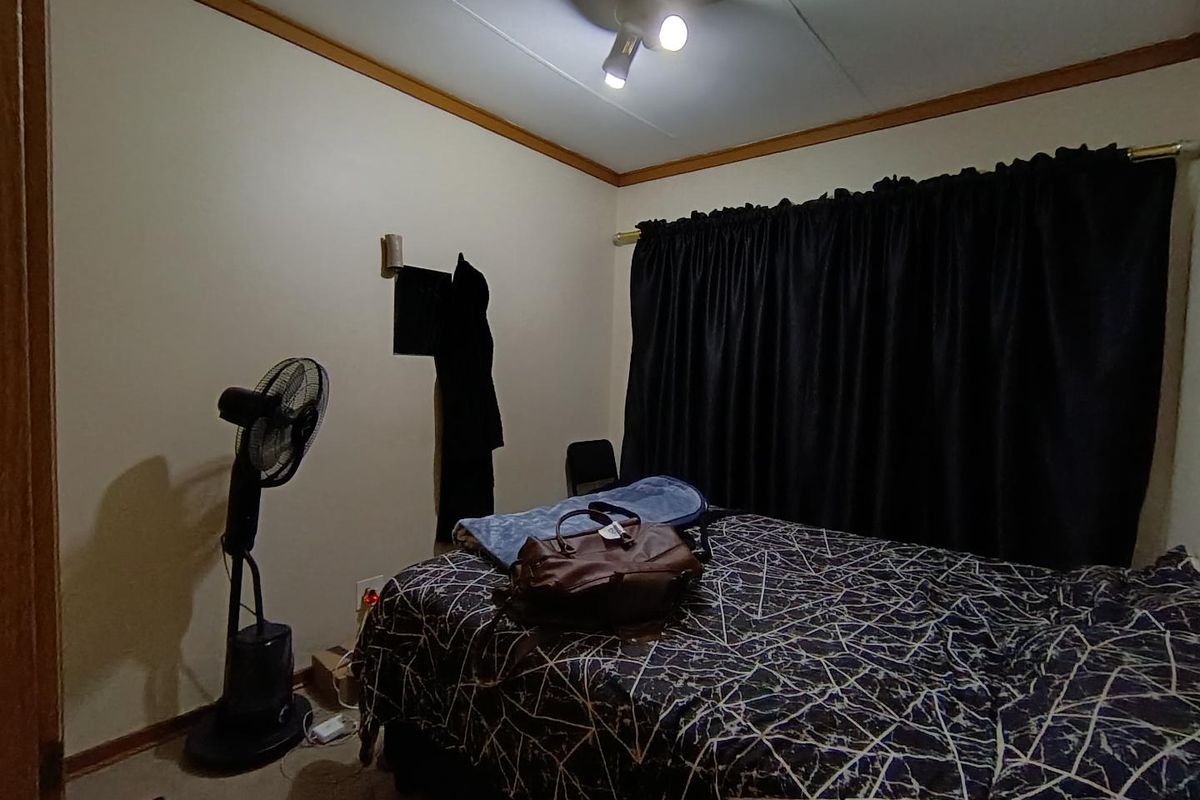 A bedroom featuring neutral walls, wooden trim, and a ceiling-mounted light fixture.