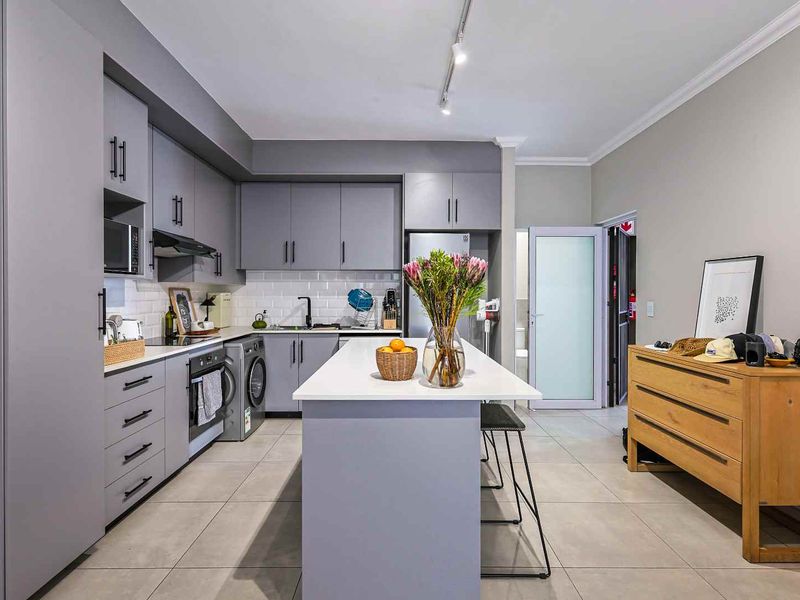 Modern kitchen featuring sleek grey cabinetry, a central island with quartz countertops, subway tile backsplash, and high-quality integrated appliances.