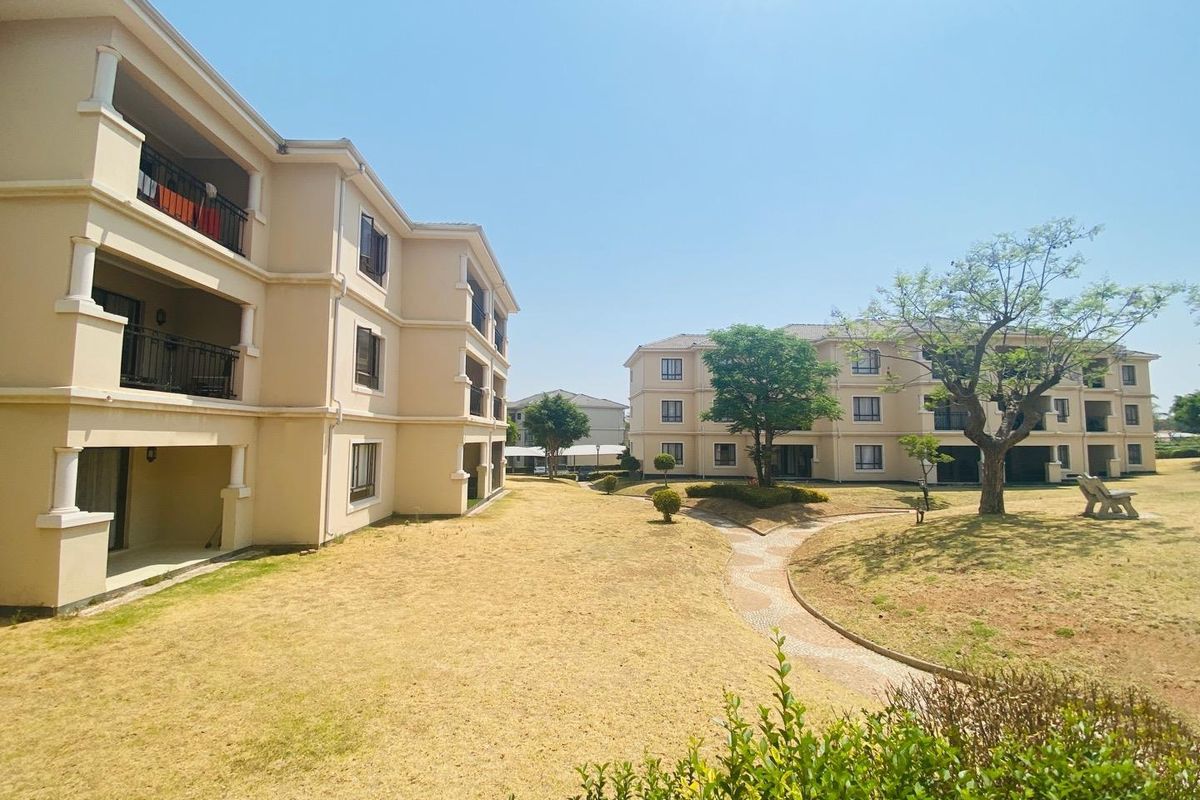 Exterior view of apartment complex buildings featuring landscaped grounds, paved walkways, and private balconies.