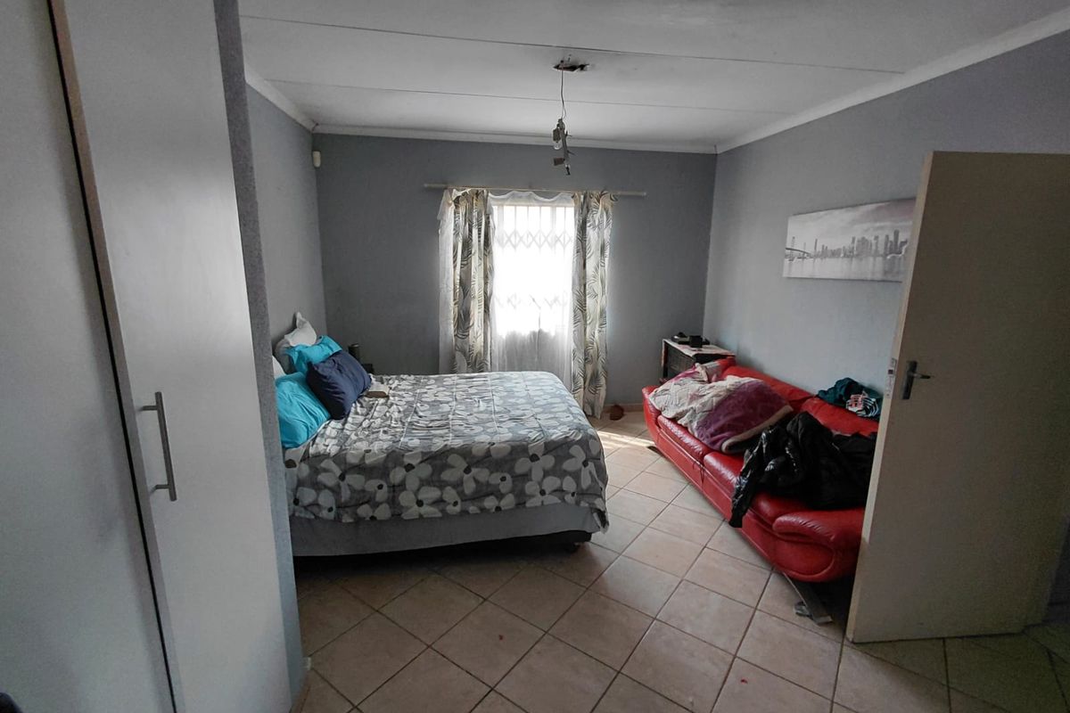 A bedroom featuring tiled flooring, a built-in wardrobe, and a window with curtains. The room requires a new light fixture.