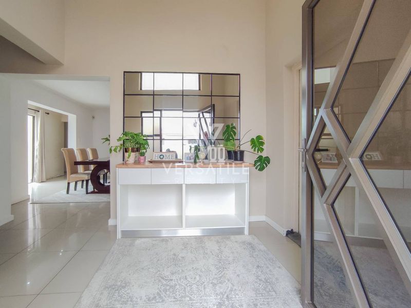 Welcoming entrance hall featuring polished tiled flooring, a modern built-in console unit, and a decorative glass panel door leading into the home.