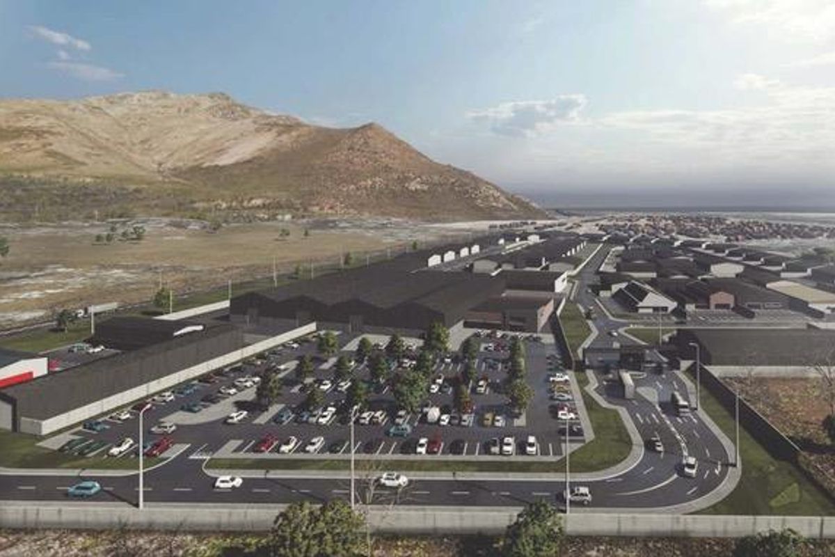 An aerial perspective of a commercial development featuring warehouse structures, extensive paved parking, and integrated access roads within a landscaped site.