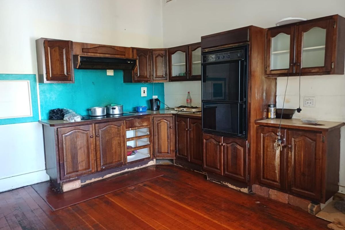 A dated kitchen featuring traditional timber cabinetry, a built-in double oven, and original timber flooring, offering significant potential for a modern renovation.