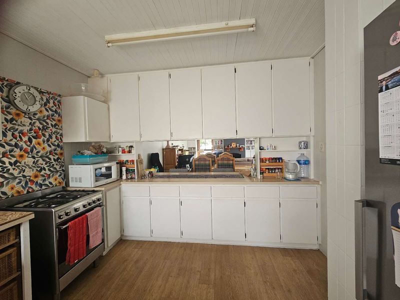 A functional kitchen featuring white built-in cabinetry, a gas stove, and a convenient pass-through window connecting to the adjacent living area.