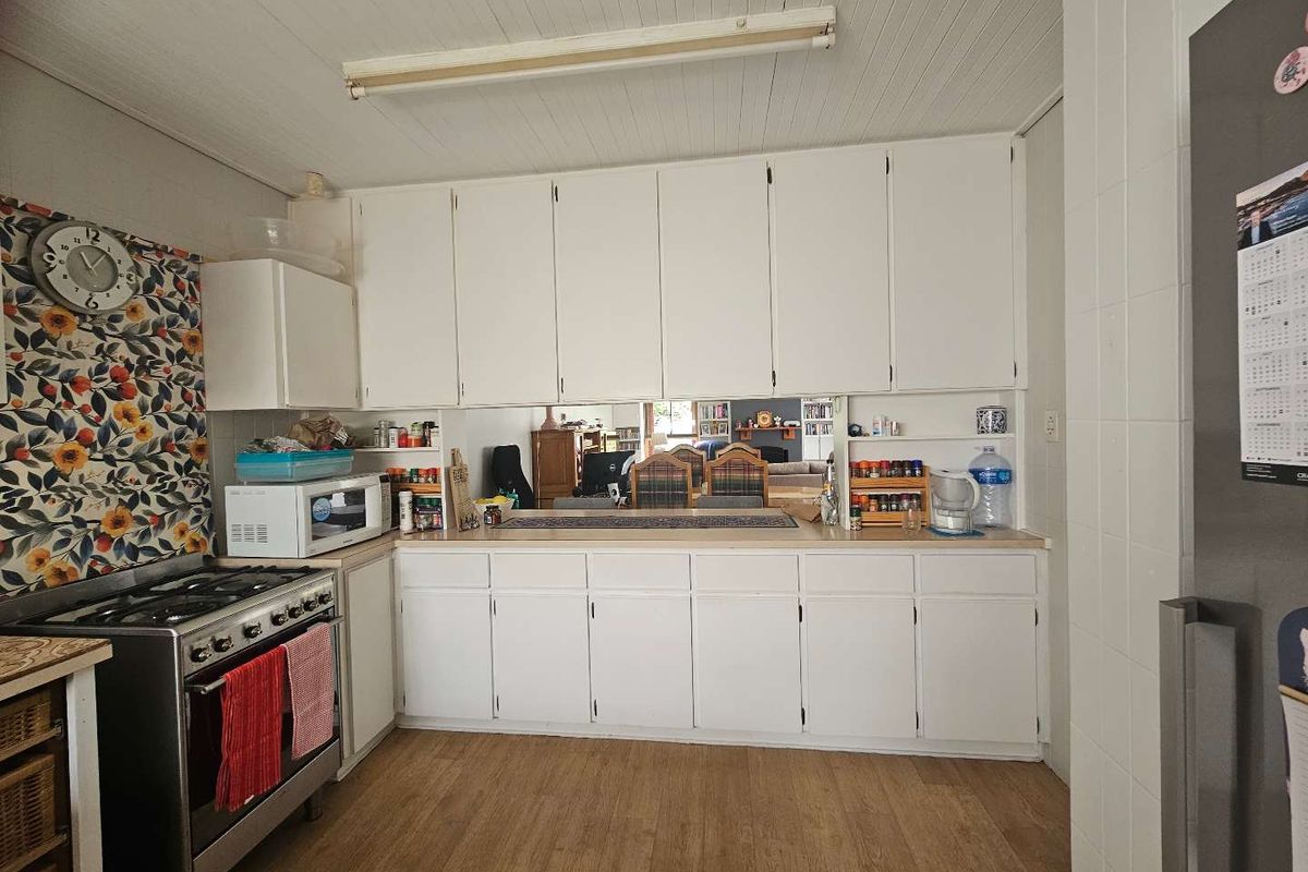 A functional kitchen featuring white built-in cabinetry, a gas stove, and a convenient pass-through window connecting to the adjacent living area.