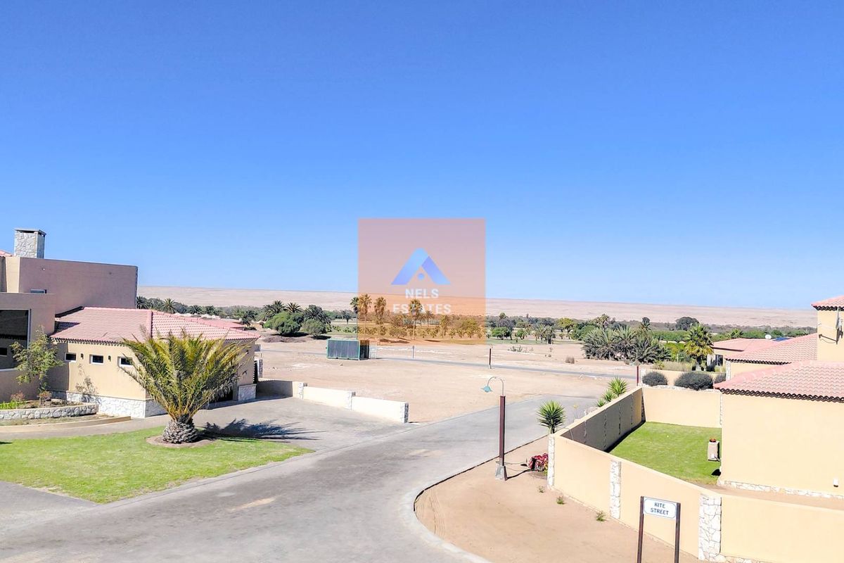 Elevated view overlooking the residential estate, featuring paved driveways, landscaped lawns, and surrounding desert landscape.