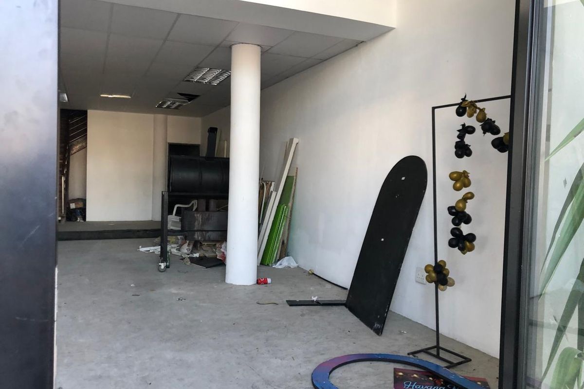 An empty retail space featuring a structural column, suspended ceiling with recessed lighting, and concrete flooring, currently requiring maintenance and cosmetic updates.