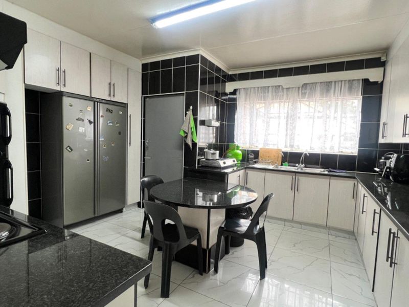 A functional kitchen featuring black granite countertops, white cabinetry, tiled flooring, and a built-in extractor fan with a dedicated breakfast nook area.