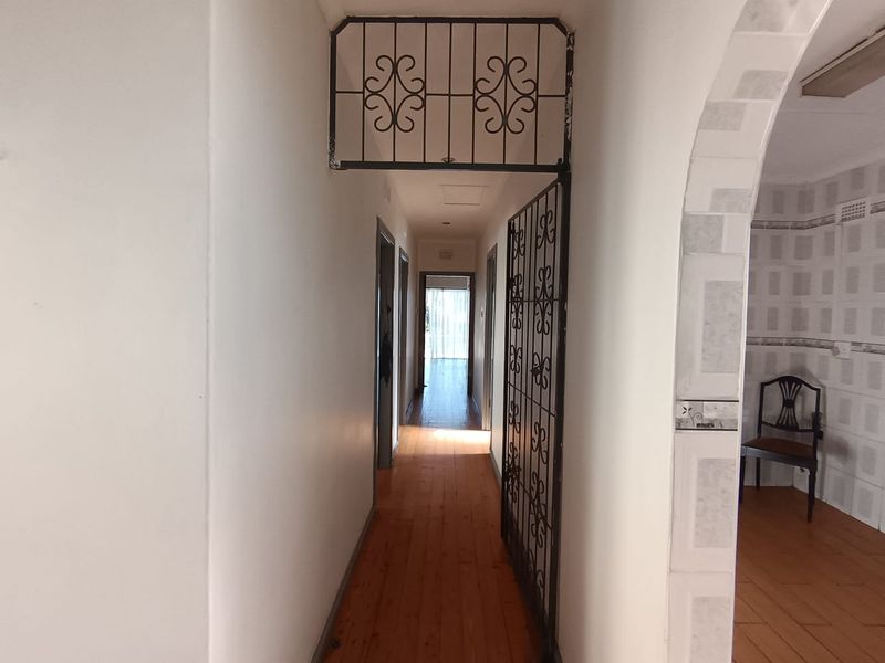 A functional hallway featuring timber flooring and a security gate, providing access to the interior rooms of the home.